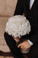 Boda ramo. blanco cortar rosas, verde semilla cabezas y hojas. verde tallos y blanco cinta y oro Boda anillos foto