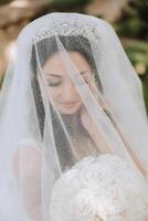 portrait of a beautiful young bride in a white dress with a long veil and a gorgeous hairstyle. Smiling bride. Wedding day. Gorgeous bride. Marriage. photo