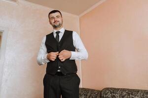 Man fastens the buttons. The groom in a suit. Close up. Man is buttoning his vest. Perfect to the last detail. Modern businessman. photo