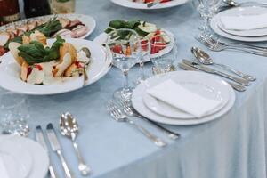 A view of wedding tables, attention to serving, with flower arrangements, expensive cutlery, plates with white napkins. photo