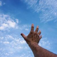 man hand gesturing and reaching the blue sky photo