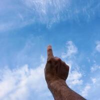 man hand gesturing and reaching the blue sky photo