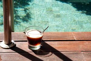 Mañana café a junto a la piscina café vaso en pie cerca nadando piscina. foto