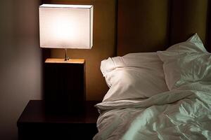 Bedside lamp turns on in bedroom at dusk. photo