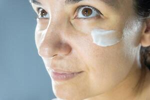 Hydration with cream. Beauty close up portrait of young woman with a healthy glowing skin is applying a skincare product. photo