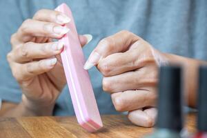 joven latín mujer formas su uñas con un rosado uña archivo. foto