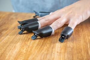 Tweezers for removing nail polish in the hands of a young woman who is waiting for the polish remover to work. photo