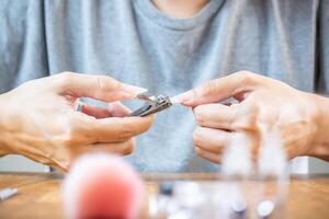 Woman cutting a nail with pliers. photo