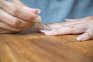 Woman's fingers using a paddle-shaped cuticle pusher. photo