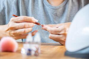 Woman using a cuticle remover, preparation before applying paint on nails. photo