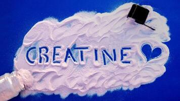 Gym composition. Highlights the word creatine with a heart on a blue background. photo