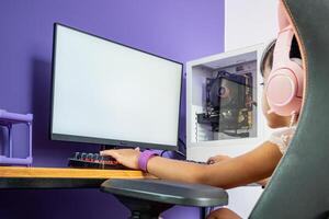 Composition with a blank monitor with a gamer girl sitting in front of it in the room. photo