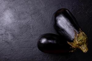 Eggplants on a black table, with low lighting. photo