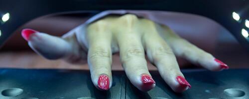 manos de un mujer dentro el uv cabina para semi permanente clavos. foto