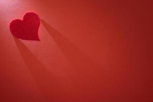 Beautiful heart illuminated from above on a red background photo