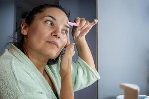 Hispanic girl using disposable eyebrow shapers photo