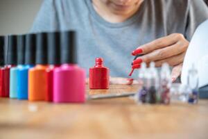 Woman painting her nails at home, using a bright red color. photo