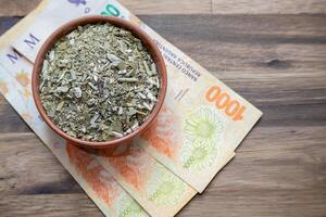 Concept of the cost of yerba mate. Argentine pesos with yerba mate in a bowl. photo