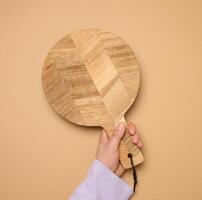 Woman's hand holding empty round wooden cutting board photo