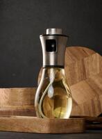 vaso transparente rociar botella lleno con girasol petróleo en un negro mesa foto