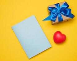 Notepad and gift box on yellow background photo