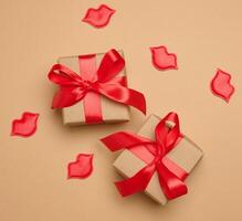 Gift box with red satin ribbon and bow on a brown background. Holiday background photo