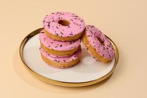 Donut covered with pink glaze and sprinkled with colorful sprinkles on a round plate, brown background photo