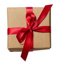 Box is wrapped in brown paper and red ribbon on a white isolated background photo