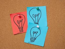 Drawn electric lightbulbs on paper sheets, signifying the concept of searching for new ideas photo