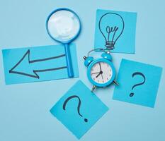 Drawn light bulbs on sheets of paper and a plastic magnifying glass photo