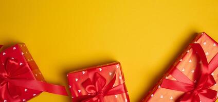 Gift box tied with a red bow on a yellow background photo