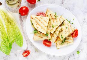 Mexican Quesadilla wrap with chicken, corn and sweet pepper on white plate. Top view photo