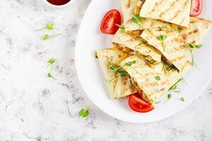 Mexican Quesadilla wrap with chicken, corn and sweet pepper on white plate. Top view photo