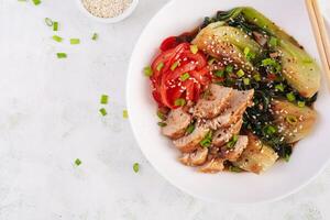 Stir fried of chicken, sweet peppers and bok choy in a bowl on the table. Stir fry pak choi. Asian food. Top view photo