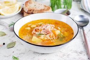 Fish soup with salmon, vegetables and rice in white bowl. Salmon soup. photo