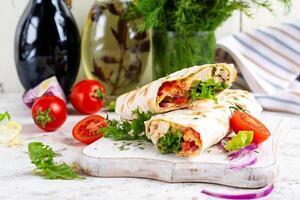 Grilled tortilla wraps with chicken and fresh vegetables on white wooden board. Chicken burrito. Mexican food. Healthy food concept. photo