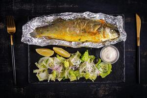 Baked sea bass and green salad. Healthy eating. Keto, ketogenic diet. Top view photo