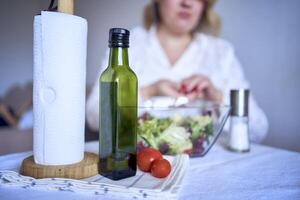 a teenage girl and her mother in pajamas are cooking and eating a fresh green and tomato salad together photo