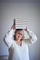 a medium-sized woman in light clothes plays with books in a light room photo