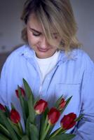 a medium-sized woman holds a bouquet of red tulips in her hands photo