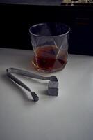 whiskey with tongs, stone cubes, wooden box and wheat on carpet photo