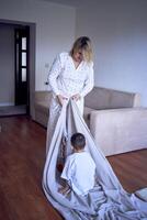 a mother plays and drags her little son on a sheet around the room photo