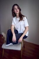 portrait of a beautiful teenage girl on a chair in a bright room in a minimalist style photo