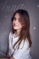 a beautiful teenage girl sits on a bed near the wall with her name written on it photo