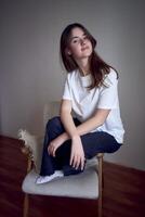 portrait of a beautiful teenage girl on a chair in a bright room in a minimalist style photo