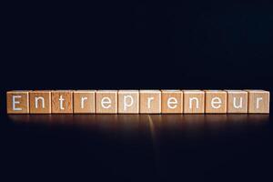 Wooden blocks form the text Entrepreneur against a black background. photo