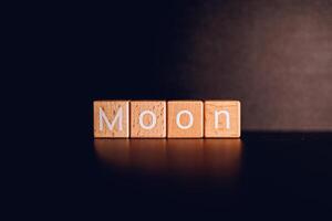 Wooden blocks form the text Moon against a black background. photo