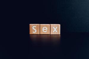 Wooden blocks form the text Sex against a black background. photo