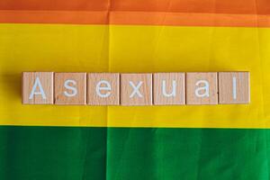 Wooden blocks form the text Asexual against a rainbow background. photo