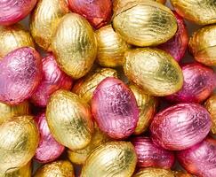 Close-up of pile of Easter candy eggs wrapped in pink and golden foil photo